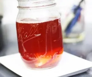 Mason jar with homemade whiskey cough syrup on a white plate