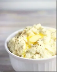 White bowl with mashed cauliflower and melted butter and pepper