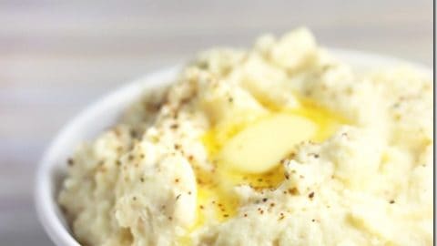 White bowl with mashed cauliflower and melted butter and pepper