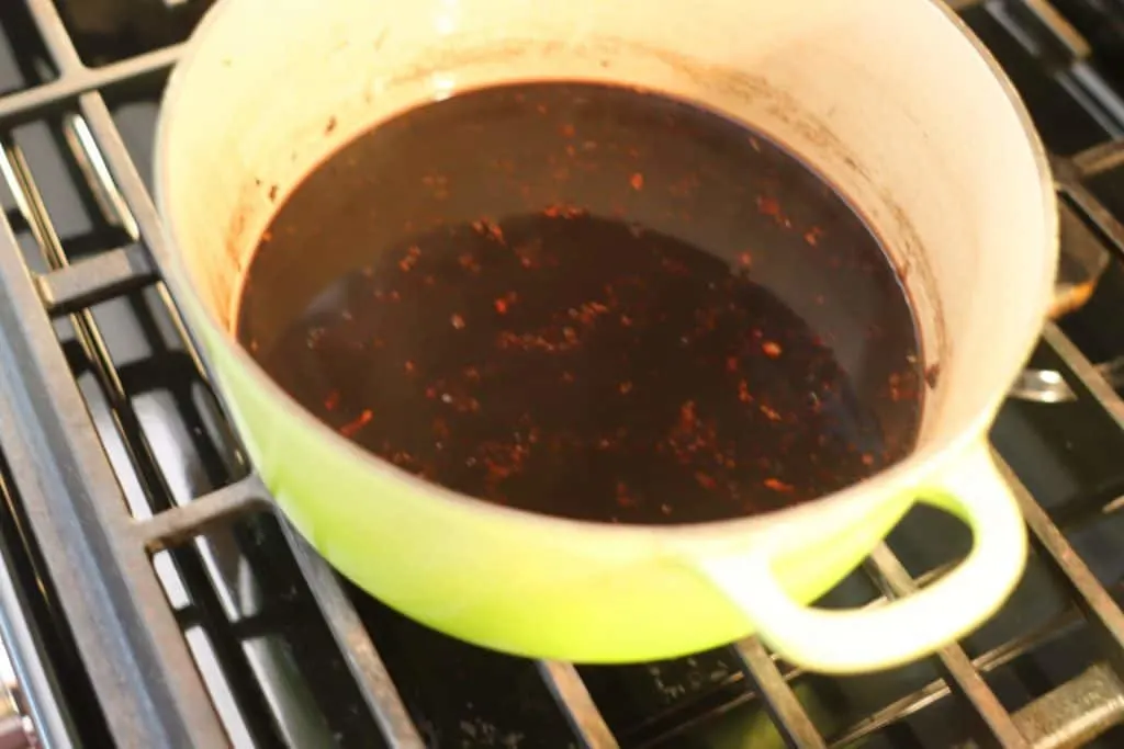 A green pot with elderberries cooking on the stove