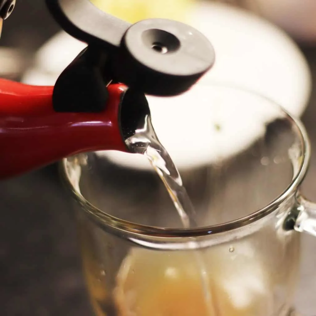 A red kettle pouring water into a cup